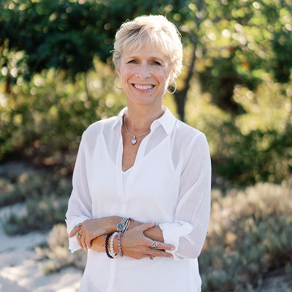 Kim Woods' client Kristen Harte in a white blouse standing outdoors, sharing a testimonial about working with Kim Woods on intuitive business growth