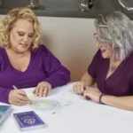 Kim Woods and 1:1 client sitting at a table, reviewing astrological charts and notes together.