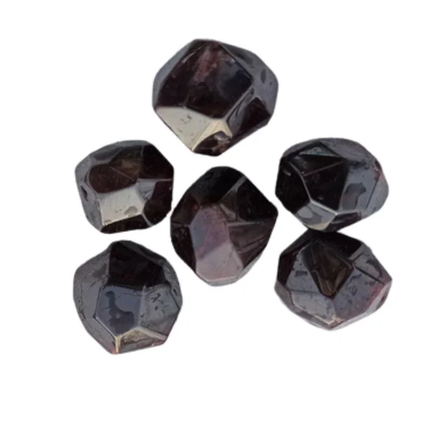 Kim Woods Master Astrologer July 2025 astrology forecast Garnet Crystal of the Month Six polished garnet stones with a deep red hue, cut into faceted geometric shapes and arranged in a loose circular pattern on a white background.