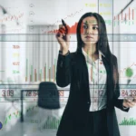 Woman in a black suit analyzes stock charts on a transparent screen, surrounded by fluctuating market data. She appears focused and strategic, reflecting August’s call to recalibrate systems and align with deeper rhythms.
