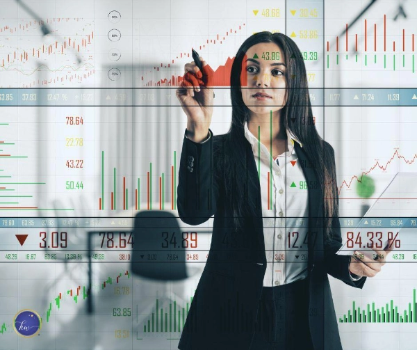 Kim Woods Master Astrologer August 2025 Forecast Economic and Business Intelligence for August Woman in a black suit analyzes stock charts on a transparent screen, surrounded by fluctuating market data. She appears focused and strategic, reflecting August’s call to recalibrate systems and align with deeper rhythms.