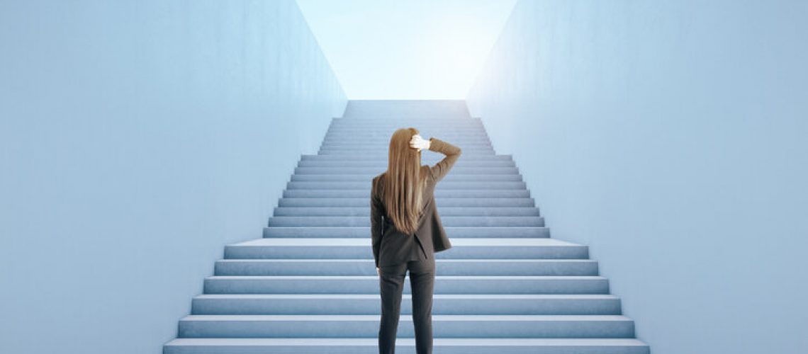 Back view of young businesswoman climbing abstract bright concrete sky stairs. Career development and growth concept