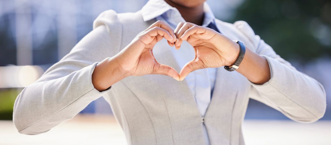 Love and a smile, a business woman makes a heart sign with her hands. Black, corporate office worker and a gesture of respect and friendship with her fingers, happy with work and success in the city